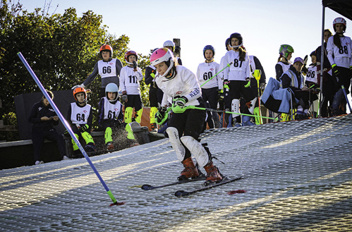A skier begins her race while others look on.